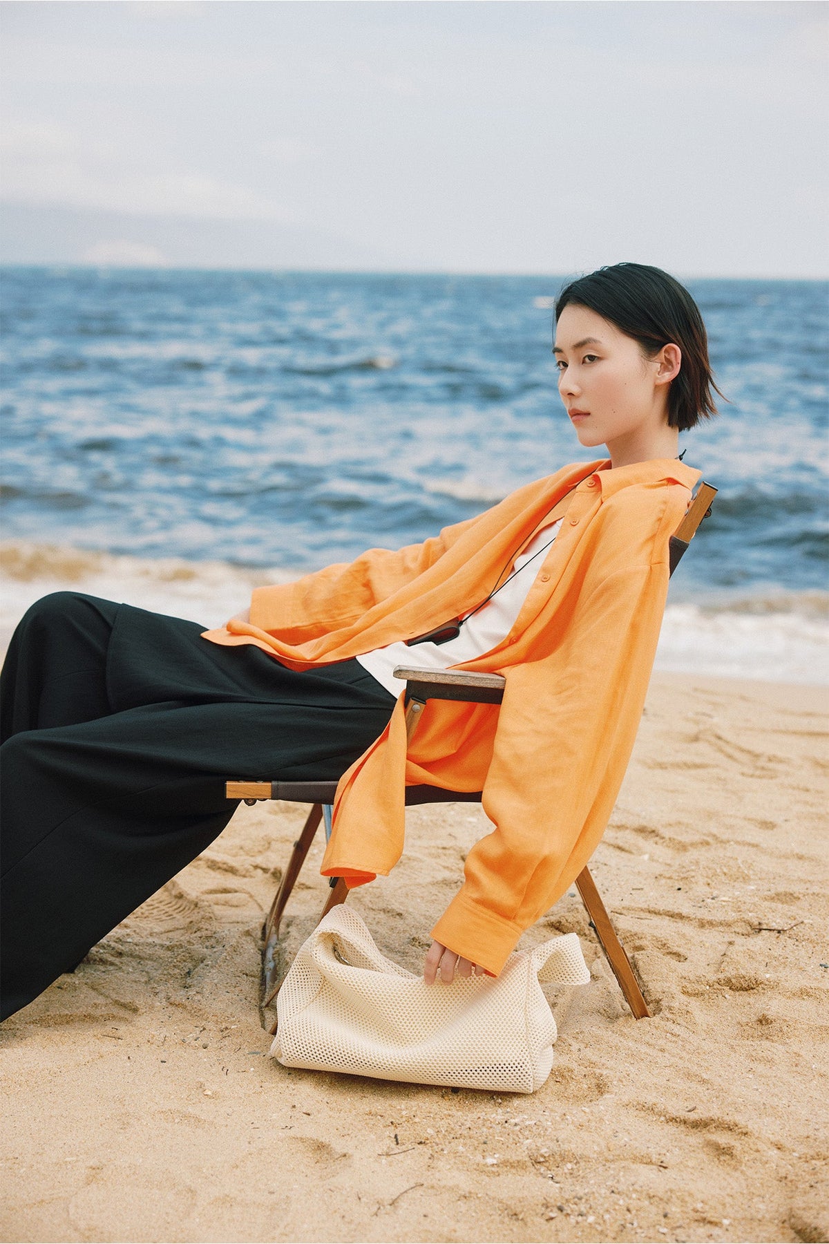 Washed orange over a cream tank and a black pleated trouser.